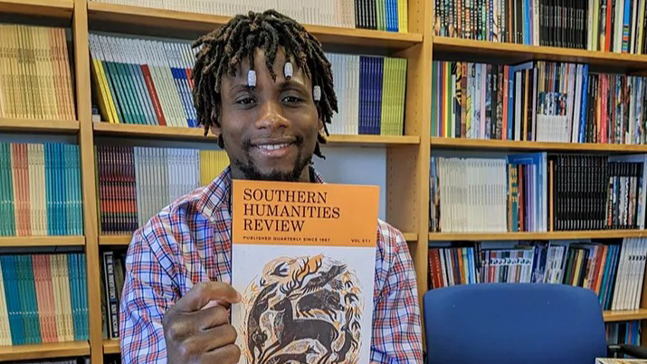 student holding up southern humanities review magazine