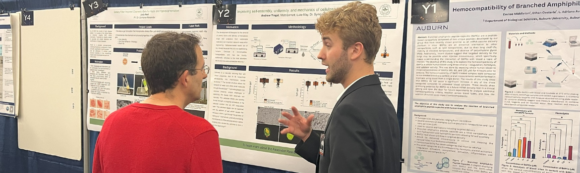 student explaining research display to attendee