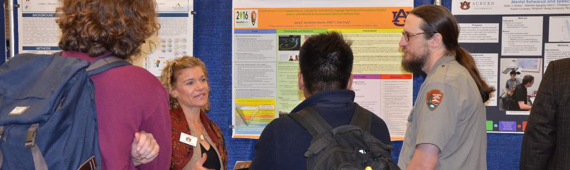 group of people discuss research on display at symposium booth