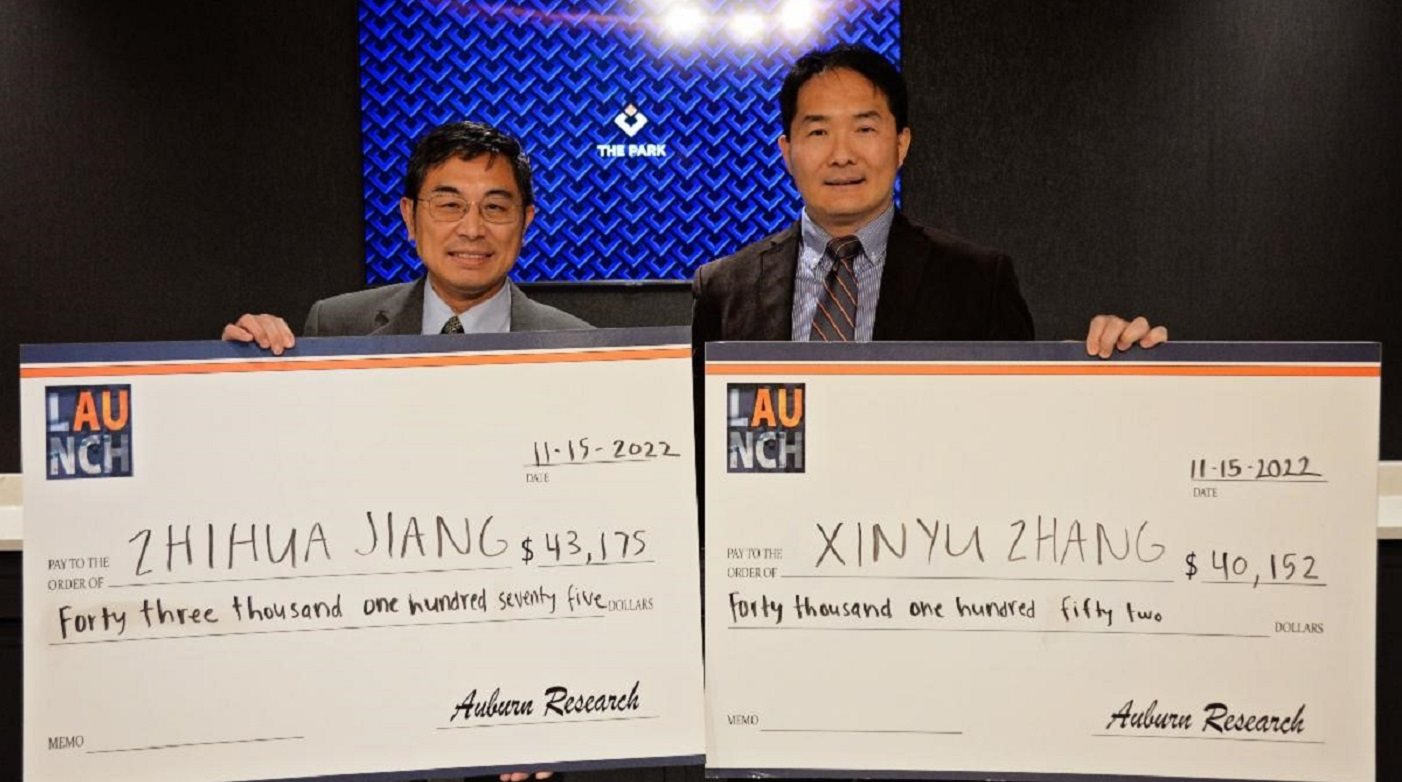 Two men holding giant checks