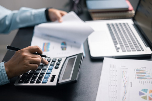 hands of accountant with printed spreadsheet, calculator and laptop